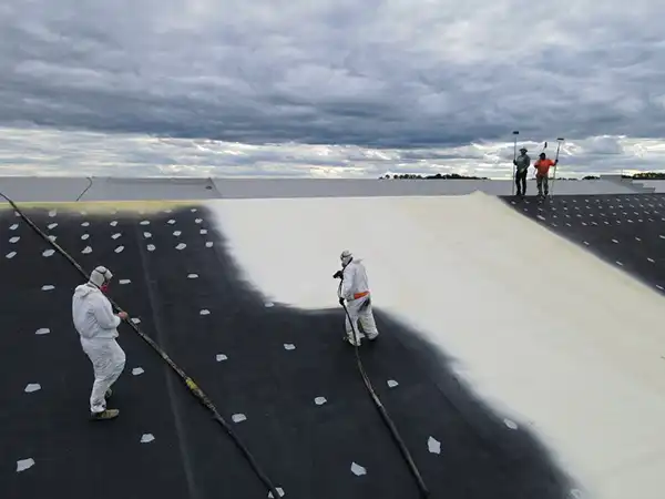 Engelmann Construction workers spraying on a form roof coating on a sloped commercial roof